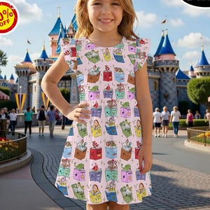 May include: A light pink dress with a repeating pattern of open books, each containing a different cartoon character. The dress has flutter sleeves and is worn by a young girl. The background shows a theme park with a castle and shops. Text on the image says "Buy More, Save More!" and "50% OFF".