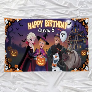May include: A Halloween-themed birthday banner with the text "HAPPY BIRTHDAY OLIVIA 5". The banner features cartoon characters, including Elsa and Anna, with a spooky castle, pumpkins, bats, and a full moon in the background.
