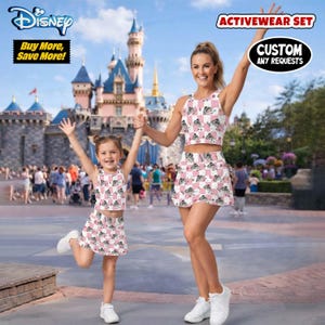 May include: Matching activewear sets for mother and child. The sets include crop tops and skirts with a pink and white checkered pattern featuring a cartoon image. The image also includes the text "Disney" and "Buy More, Save More!"