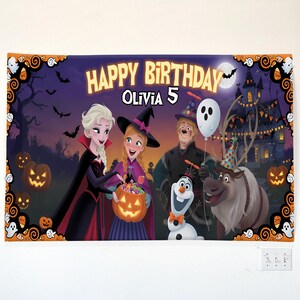 May include: A Halloween-themed birthday banner featuring characters from Frozen. The banner reads "Happy Birthday Olivia 5" with illustrations of Elsa, Anna, Olaf, Kristoff, and Sven in Halloween costumes. The background includes a haunted house, pumpkins, and bats.