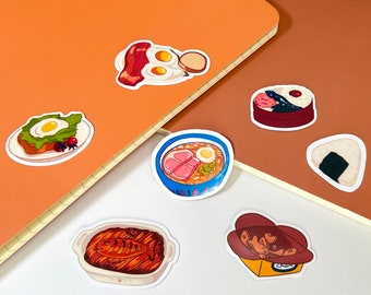 Op de afbeelding: Een set kleurrijke stickers met verschillende Japanse gerechten, waaronder ramen, gebakken vis, onigiri en een ontbijt-sandwich. De stickers zijn op een bruine en oranje achtergrond.