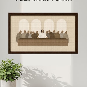 May include: A framed cross-stitch pattern showing a religious scene with figures at a table. The artwork has a dark brown frame and the text "Cross Stitch Pattern" at the top. The scene is rendered in shades of brown and beige.
