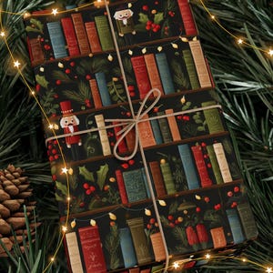 May include: Wrapped gift with a black background featuring a bookshelf design with colourful books, holly, and string lights. The gift is tied with twine and decorated with a nutcracker. Festive holiday theme.