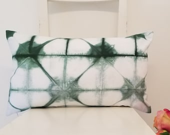 May include: A rectangular cushion featuring a white backdrop and a geometric design in varying shades of green. The cushion is displayed on a white chair, highlighting its pattern and texture. The cushion measures approximately 30 cm by 50 cm.