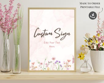May include: A framed sign with the words "Custom Sign" in elegant script. The background has a watercolor effect with pink hues. The bottom of the sign features a floral border. The words "Edit Your Text Here" are below the main text.