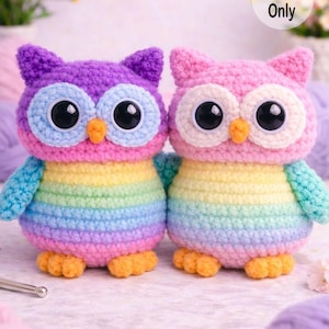 May include: Two handmade crochet owl toys. One owl is purple, blue, and rainbow-colored, and the other is pink, white, and rainbow-colored. Both have large black eyes, orange beaks, and the text "Pattern Only".