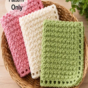 Op de afbeelding: Een rieten mand bevat vier gehaakte vierkanten in roze, crème en groen. De vierkanten hebben een getextureerd steekpatroon en een decoratieve rand. De tekst "Pattern Only" is linksboven zichtbaar.