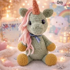 K&ouml;nnte beinhalten: Ein geh&auml;keltes Einhorn-Pl&uuml;schtier in weichem Gr&uuml;n, mit einem braunen Horn, rosa und wei&szlig;er M&auml;hne und gelben Hufen. Das Einhorn hat gro&szlig;e schwarze Augen und ein blaues Band. Der Text "Pattern Only" befindet sich oben rechts.