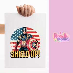 May include: A rectangular white print featuring a graphic illustration of Captain America in a blue, red, and white suit with a matching shield. Behind the character is a circular American flag design. The text SHIELD UP! appears in yellow.