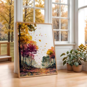 以下が含まれることがあります： 秋の森の風景を描いた、額入りの水彩画プリント。鮮やかな黄色、オレンジ、赤色の葉を持つ木々が描かれ、森の中を抜ける小道があります。フレームは明るい色の木材で作られています。