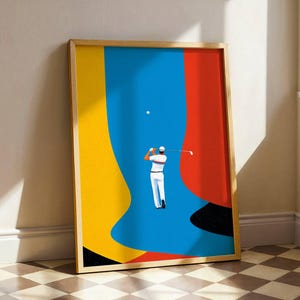 Könnte beinhalten: Gerahmter Kunstdruck mit einem Golfer in weißer Kleidung beim Abschlag. Der Hintergrund ist eine kühne Komposition aus Blau, Gelb und Rot. Das Kunstwerk befindet sich in einem Holzrahmen und lehnt an einer Wand.