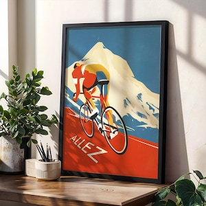 May include: A framed art print depicting a cyclist racing uphill. The artwork has a vintage style with a red, yellow, and blue colour scheme. The word "ALLEZ" is printed in white on a red background.