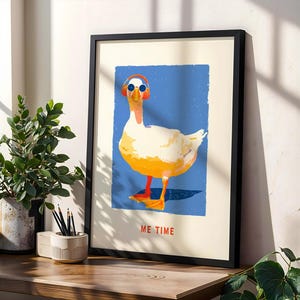 Könnte beinhalten: Gerahmter Kunstdruck mit einer Illustration einer Gans mit Sonnenbrille und Kopfhörern vor blauem Hintergrund. Die Gans ist weiß und gelb mit orangefarbenen Füßen. Der Text "ME TIME" ist rot gedruckt.