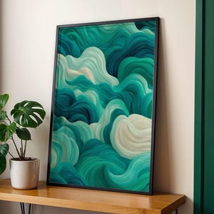 Könnte beinhalten: Ein gerahmter Kunstdruck mit einem abstrakten Design aus wirbelnden türkisfarbenen, türkisen und weißen Pinselstrichen. Das Kunstwerk befindet sich in einem schwarzen Rahmen und lehnt an einer Wand. Eine Topfpflanze steht auf einer Holzoberfläche.