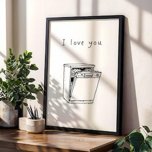 Peut inclure: Impression d'art encadrée en noir avec un dessin au trait d'un lave-vaisselle et les mots "I love you" au-dessus. L'œuvre d'art monochrome est affichée sur une surface en bois.