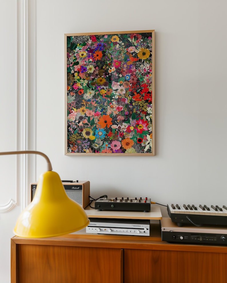 K&ouml;nnte beinhalten: Ein gerahmter Kunstdruck mit bunten Blumen in Rot-, Orange-, Gelb-, Blau- und Lilat&ouml;nen. Das Kunstwerk h&auml;ngt an einer wei&szlig;en Wand &uuml;ber einem Holzschrank mit einer gelben Lampe und Musikequipment.