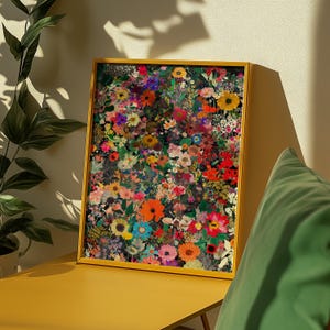 K&ouml;nnte beinhalten: Ein gerahmter Kunstdruck mit Blumen, der eine dichte Anordnung farbenfroher Blumen zeigt. Das Kunstwerk zeigt Bl&uuml;ten in Rot-, Orange-, Gelb-, Rosa- und Lilat&ouml;nen vor einem dunklen Hintergrund. Der Rahmen hat eine warme Goldfarbe.
