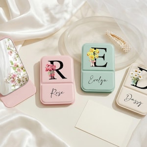 May include: A white ceramic mug with a black handle and the text "But First, Coffee" in a bold, black font. The mug is set against a neutral background, highlighting its simple design.