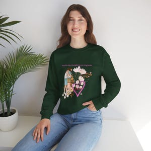 Peut inclure: Sweat-shirt vert foncé avec un motif de deux personnes s'embrassant à l'intérieur d'un cœur rose, entouré de fleurs. Le texte "Every love story is beautiful, but ours is my favorite" est imprimé au-dessus. Manches longues.