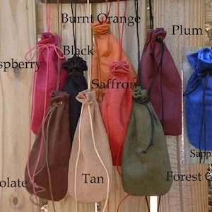 May include: Ten drawstring pouches in various colors, including black, tan, chocolate, raspberry, burnt orange, saffron, plum, forest green, and sapphire. The pouches are made of leather and have a drawstring closure.