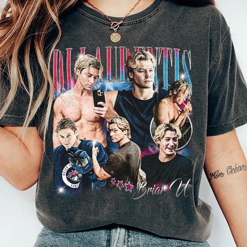 Pode incluir: T-shirt cinza escuro com uma colagem de imagens de um homem com cabelo loiro. A camisa tem o texto "LAURENTIS" em uma fonte retr&ocirc;, com o nome "Briar U" abaixo. O design inclui estrelas e uma imagem com tema de h&oacute;quei.