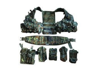 Puede incluir: Un conjunto de chaleco y cinturón tácticos con estampado de camuflaje. El chaleco tiene múltiples bolsillos y bolsas, y el cinturón incluye bolsas adicionales. Diseñado para uso militar o actividades al aire libre.
