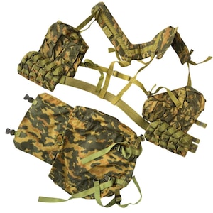 May include: A military-style tactical vest in a camouflage pattern of brown, green, and tan. The vest features multiple pouches, straps, and adjustable components. The design includes a waist belt and shoulder straps.
