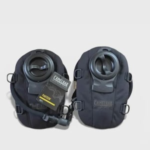 以下が含まれることがあります： 黒色のCamelBakハイドレーションパック2つ。中央の注入口と飲用チューブが付いています。1つのパックには、CamelBakのロゴと「Protein」の文字が入った小さなカードが付いています。アウトドアアクティビティ向けに設計されています。