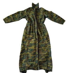May include: A long, camouflage-patterned coat with a high collar and a drawstring waist. The coat features a zipper closure and pockets. The color palette includes shades of green, brown, and tan, creating a military-inspired aesthetic.