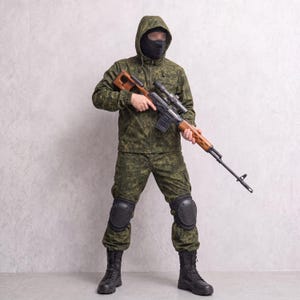 May include: A green digital camouflage hooded jacket and matching trousers worn with a black balaclava, black knee pads, and black tactical boots. The outfit is paired with a long-barreled rifle featuring a wooden stock and a mounted scope.