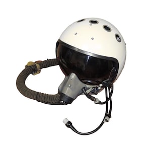 Peut inclure: Casque de pilote vintage crème avec une visière sombre et un masque à oxygène gris. Le casque comporte plusieurs petits orifices circulaires et est relié à un tuyau ondulé et à des fils. Un équipement d'aviation classique.