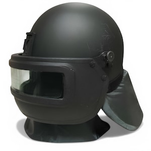 May include: A matte black ballistic helmet with a clear visor. The helmet has a rounded top and a protective neck guard. The visor is rectangular and the helmet has a few scratches. The helmet is designed for protection.