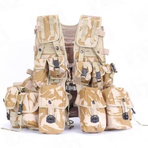May include: A tan and brown camouflage tactical vest with multiple pouches and compartments. The vest has adjustable straps and black buckles. The design is a desert camouflage pattern, suitable for military or outdoor use.