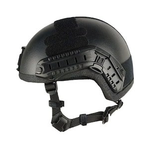 Può includere: Casco tattico nero con sottogola regolabile e guide laterali. Il casco presenta un design curvo con una superficie strutturata e una toppa in velcro sulla parte superiore. Ideale per attività all'aperto e protezione.