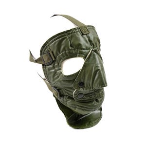 Peut inclure: Masque facial vert olive avec ouvertures pour les yeux et le nez. Le masque est doté de sangles réglables et de fermetures à boutons. Le masque semble être fait d'un matériau durable, possiblement résistant à l'eau. La conception suggère un but protecteur ou tactique.