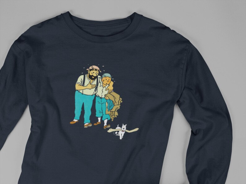 May include: Navy blue long-sleeve shirt featuring a cartoon illustration of two men and a dog. The men are in blue pants and white shirts. The dog is white. The shirt is made of a soft, comfortable material.