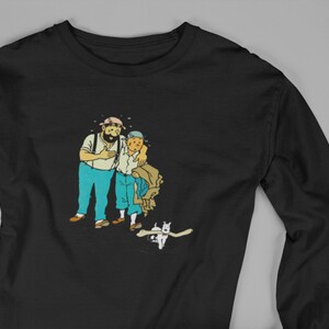 May include: Black long-sleeve shirt featuring a cartoon illustration of two men and a dog. The men are in blue pants and white shirts, with one wearing a hat. The dog is white with a bone in its mouth.
