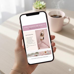 May include: A smartphone displays a pink and white graphic with the text "8-MINUTE SOFT START WARM-UP" and "Move with Ease. Feel Good." The screen shows a woman in activewear demonstrating yoga poses. A cup of coffee and a succulent plant are in the background.