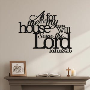 Könnte beinhalten: Schwarze Metall-Wandkunst mit dem Text "As for me and my house we will serve the Lord Joshua24:15". Ein gerahmtes Familienfoto, ein offenes Buch, ein Holzkreuz und eine brennende Kerze auf einem grauen Kaminsims.