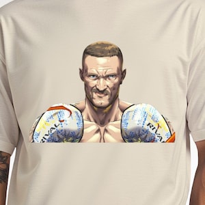 May include: Beige t-shirt featuring a detailed illustration of a boxer with boxing gloves. The gloves are white, blue, and orange, with the word "RIVAL" printed on them. The boxer has a determined expression.