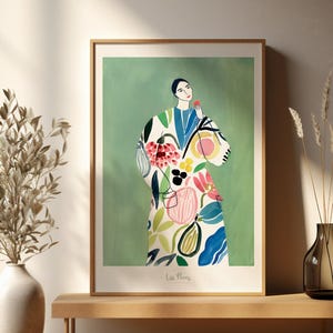 Könnte beinhalten: Ein gerahmter Kunstdruck mit einer Frau in einem floral gemusterten Mantel, die eine rote Blume hält. Das Kunstwerk hat einen grünen Hintergrund und wird auf einer Holzbank ausgestellt. Der Druck ist in einem Holzrahmen.