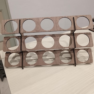 Puede incluir: Un especiero de madera de tres niveles, cada uno con cuatro aberturas circulares. El especiero es de madera marrón claro y está diseñado para guardar pequeños frascos o recipientes. El diseño es sencillo y funcional.