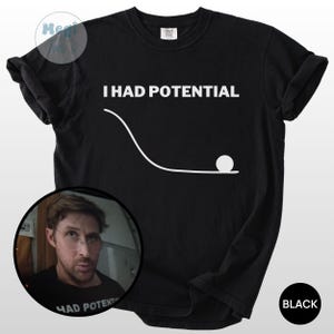 May include: Black t-shirt with the white text "I HAD POTENTIAL" and a graphic of a ball at the end of a curved line. A circular image of a man wearing glasses is in the lower left corner. The word "BLACK" is in a black circle in the lower right.