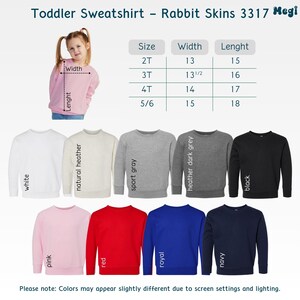Puede incluir: Una variedad de sudaderas para ni&ntilde;os peque&ntilde;os en diferentes colores, incluyendo blanco, rosa, rojo, azul real y marino. La imagen tambi&eacute;n muestra una tabla de tallas con medidas en cm para el ancho y el largo. El texto dice "Toddler Sweatshirt - Rabbit Skins 3317 Megi."