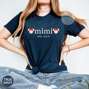 May include: True navy t-shirt with the word "mimi" in white, featuring Mickey Mouse ears on each side. Below the word is "Est. 2026" in white. The shirt is a dark blue color.