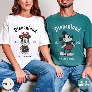Puede incluir: Dos camisetas, una blanca y otra azul abeto, con el logotipo de Disneyland y gr&aacute;ficos de Minnie Mouse y Mickey Mouse. Las camisetas tambi&eacute;n incluyen el texto "est. 1955" y "CALIFORNIA".