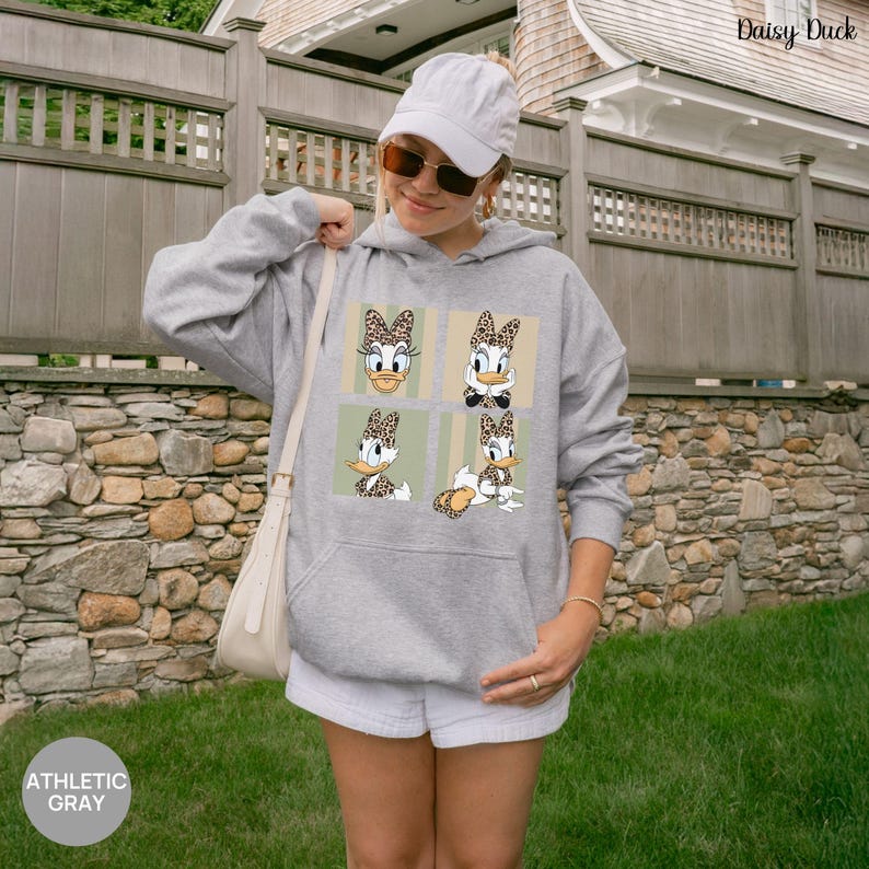 May include: Athletic gray hoodie featuring four Daisy Duck images with leopard print accents. The hoodie has a front pocket and a drawstring hood. The text "Daisy Duck" is printed on the top right corner. The bottom left corner of the image has the text "ATHLETIC GRAY".