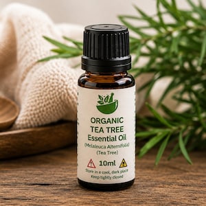 May include: A small amber glass bottle of organic tea tree essential oil with a black cap. The white label features a green mortar and pestle icon, the text Organic Tea Tree Essential Oil, Melaleuca Alternifolia, 10ml, and safety warnings.