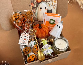 Könnte beinhalten: Eine Pappschachtel mit einem Halloween-Geschenkset: ein durchsichtiger Beutel mit Kürbis-Motiv und Boo-Yah-Anhänger, ein kleiner orangefarbener Stoffkürbis, eine weiße Geisterfigur, ein Glas Honig, ein goldener Löffel und ein Kürbisgewürz-Teebeutel.