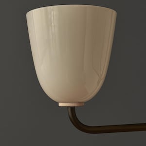 May include: A cream-colored, tulip-shaped light fixture with a dark bronze arm. The fixture has a smooth, glossy finish and a small, textured ring at the base. The background is a solid, dark gray.